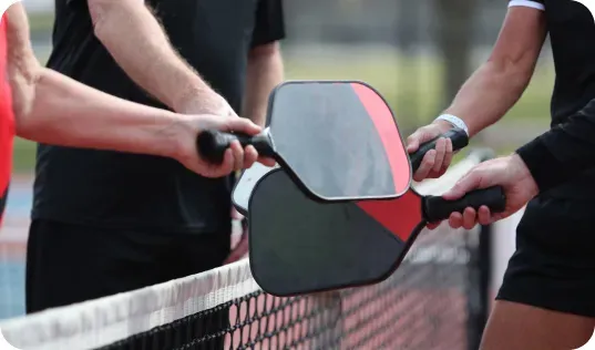 Pickleball players extending paddles together in a gesture of sportsmanship