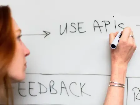 Person writing “Use APIs” on a whiteboard during an address lookup workflow discussion