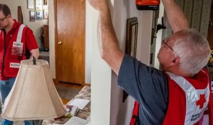 red cross volunteer drilling into a wall