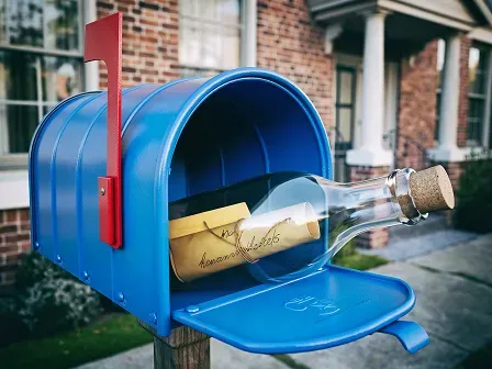 Image showing a message in a bottle inside an open mailbox.