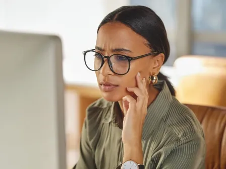 Person looking at computer screen with a confused look on her face