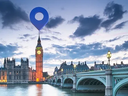 Big Ben and Westminster Bridge in London with a large blue map pin marker above the clock tower