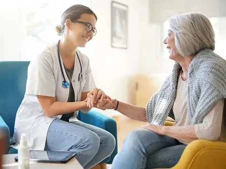 Doctor holding hand with a patient as they hold a conversation