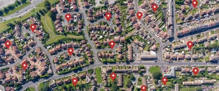 Aerial view of multiple homes with red pins on rooftops