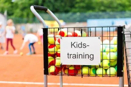 Training red and yellow tennis balls in a basket for kids.